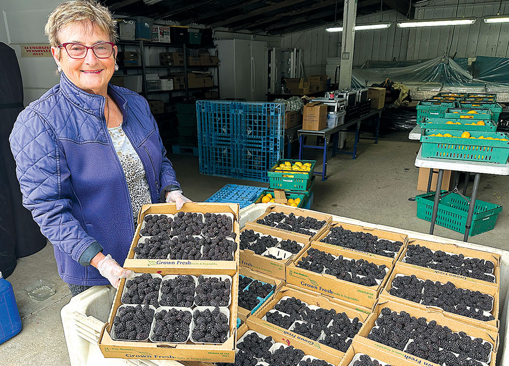 Woman holding a flat of berries in a berry warehouse
