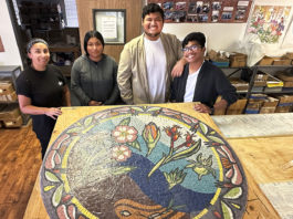 Community Mosaic Projects Move Forward Four young people standing behind a round mosaic artwork