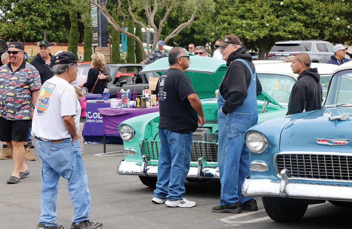 People check out a string of early-day cars and trucks Saturday in East Lake Village Shopping Center