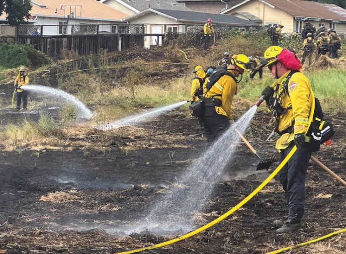 firefighters douse a grass fire on the 300 block of Amesti Road Friday.